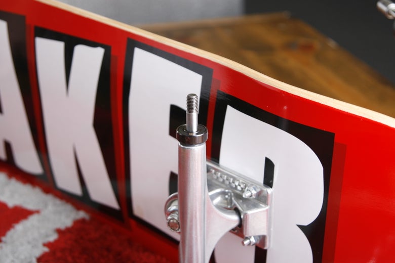 A person places a wheel bearing on a skateboard truck axel.