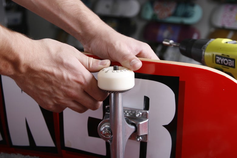 A person places a skateboard wheel on top of the wheel bearing and pushes the bearing into the wheel. 