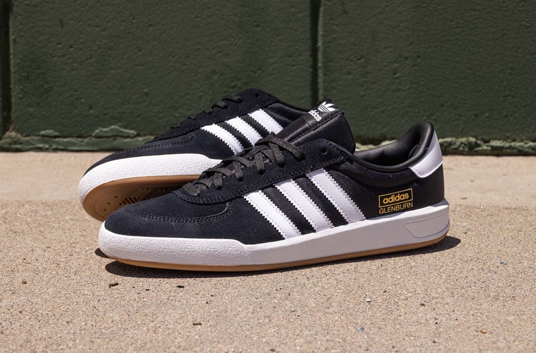 Black and white adidas Glenburn shoes placed outdoors.