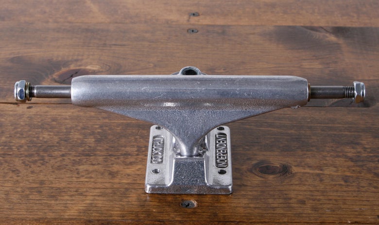 An Independent Stage 11 Standard skateboard truck sits on a wood table.